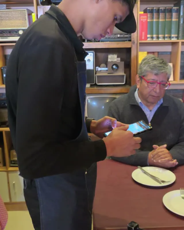 Garzón tomando el pedido con el celular junto a la mesa